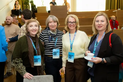Four attendees standing with coffee in the venue foyer between sessions.